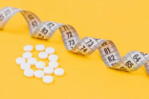 Pills and measuring tape symbolizing weight loss treatments—illustrating the need for LegitScript certification for weight loss clinics to advertise online